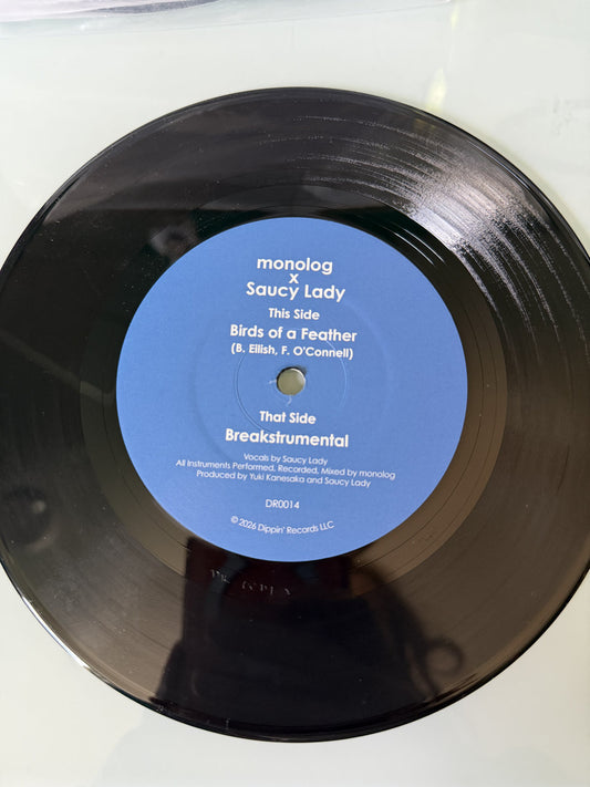 Lado A del vinilo 7" monolog x Saucy Lady – Birds Of A Feather sobre el disco, con etiqueta azul, créditos visibles y catálogo DR0014 de Dippin' Records.