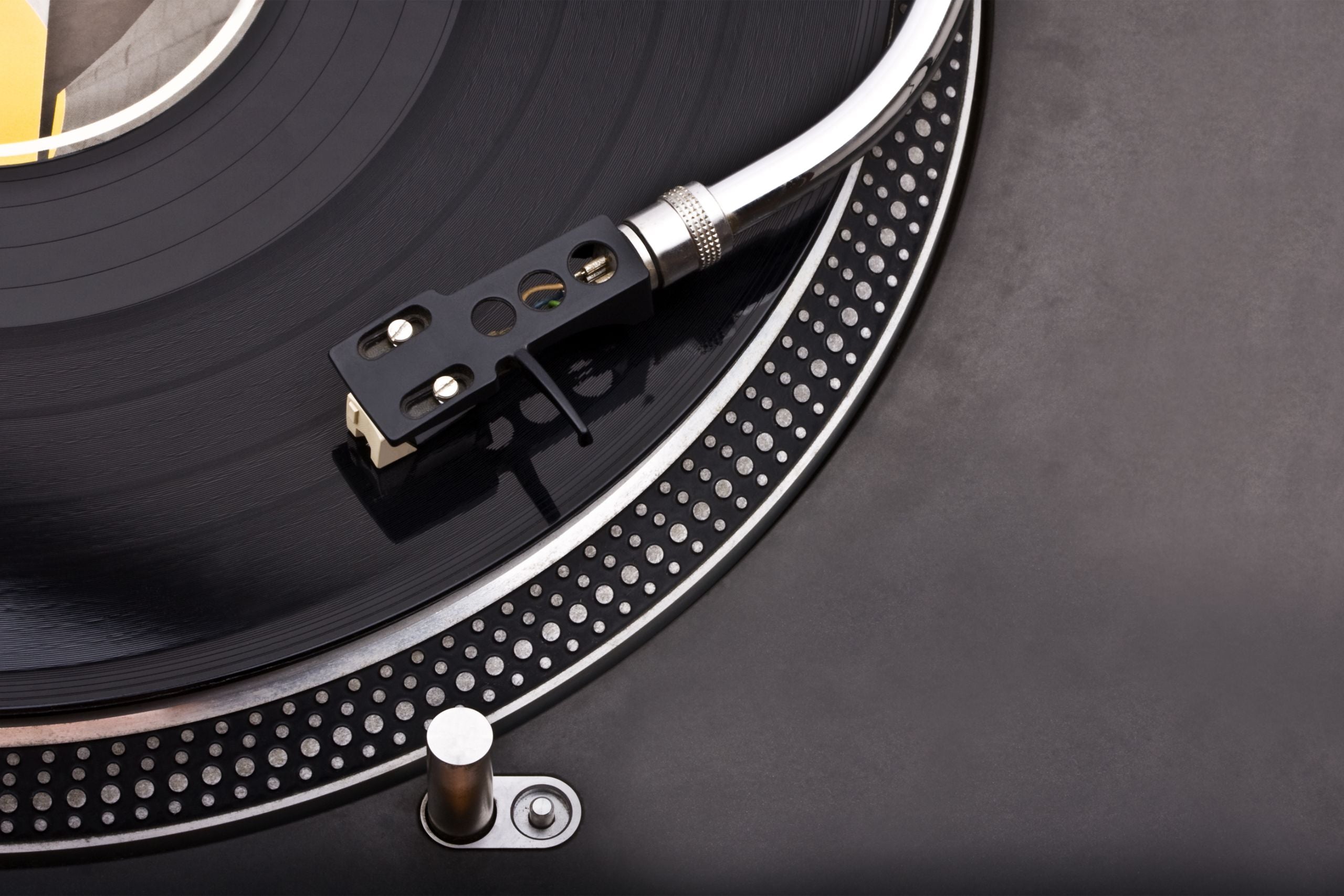 Una mano sostiene un disco de vinilo negro frente a un fondo amarillo vibrante, destacando el estilo único de nuestra tienda de discos de vinilo para DJs.