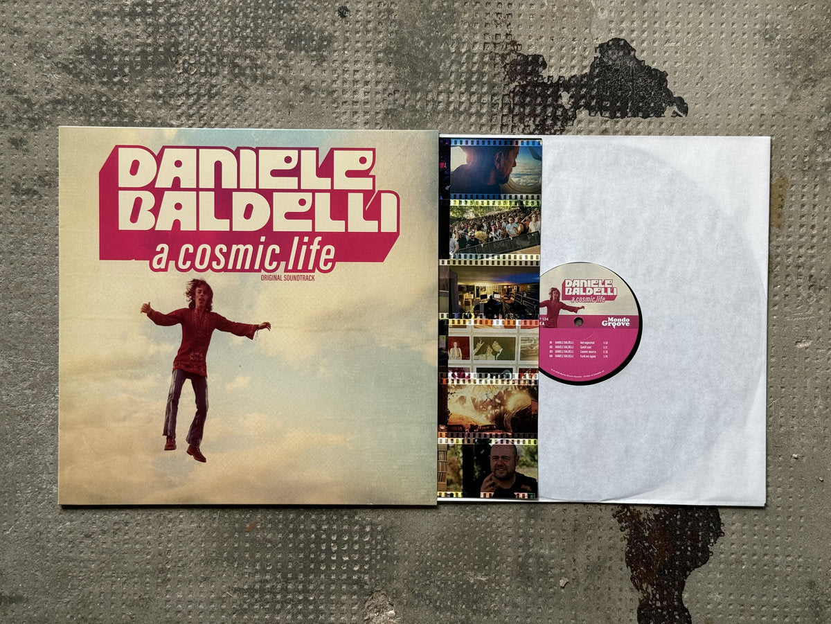 Funda e interior del vinilo Daniele Baldelli – A Cosmic Life (Original Soundtrack), LP de Mondo Groove con insert fotográfico y etiqueta central rosa con pistas visibles.
