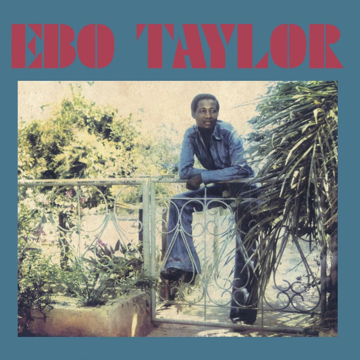 Portada del vinilo Ebo Taylor – Ebo Taylor, reedición LP en Strut, con foto del artista apoyado en una verja y diseño azul clásico.