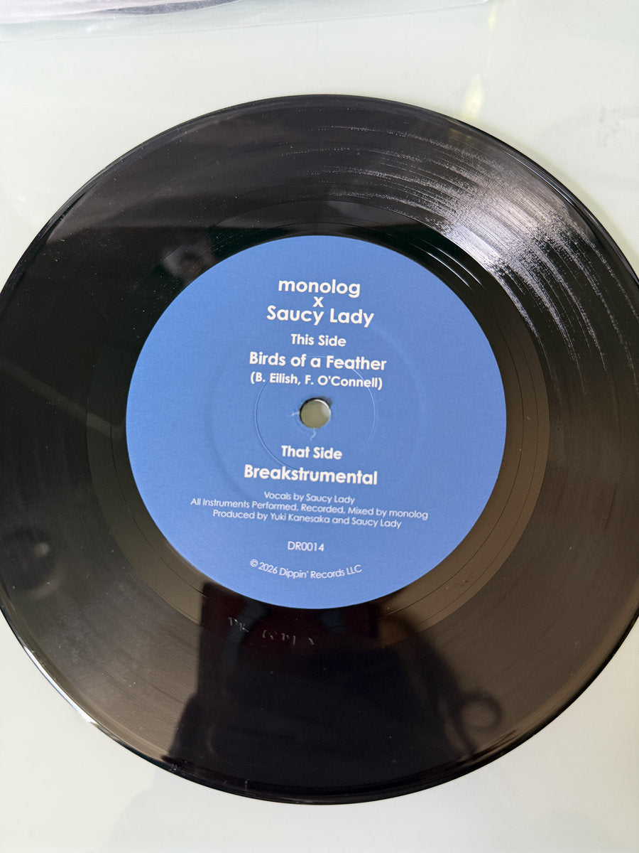 Lado A del vinilo 7" monolog x Saucy Lady – Birds Of A Feather sobre el disco, con etiqueta azul, créditos visibles y catálogo DR0014 de Dippin' Records.