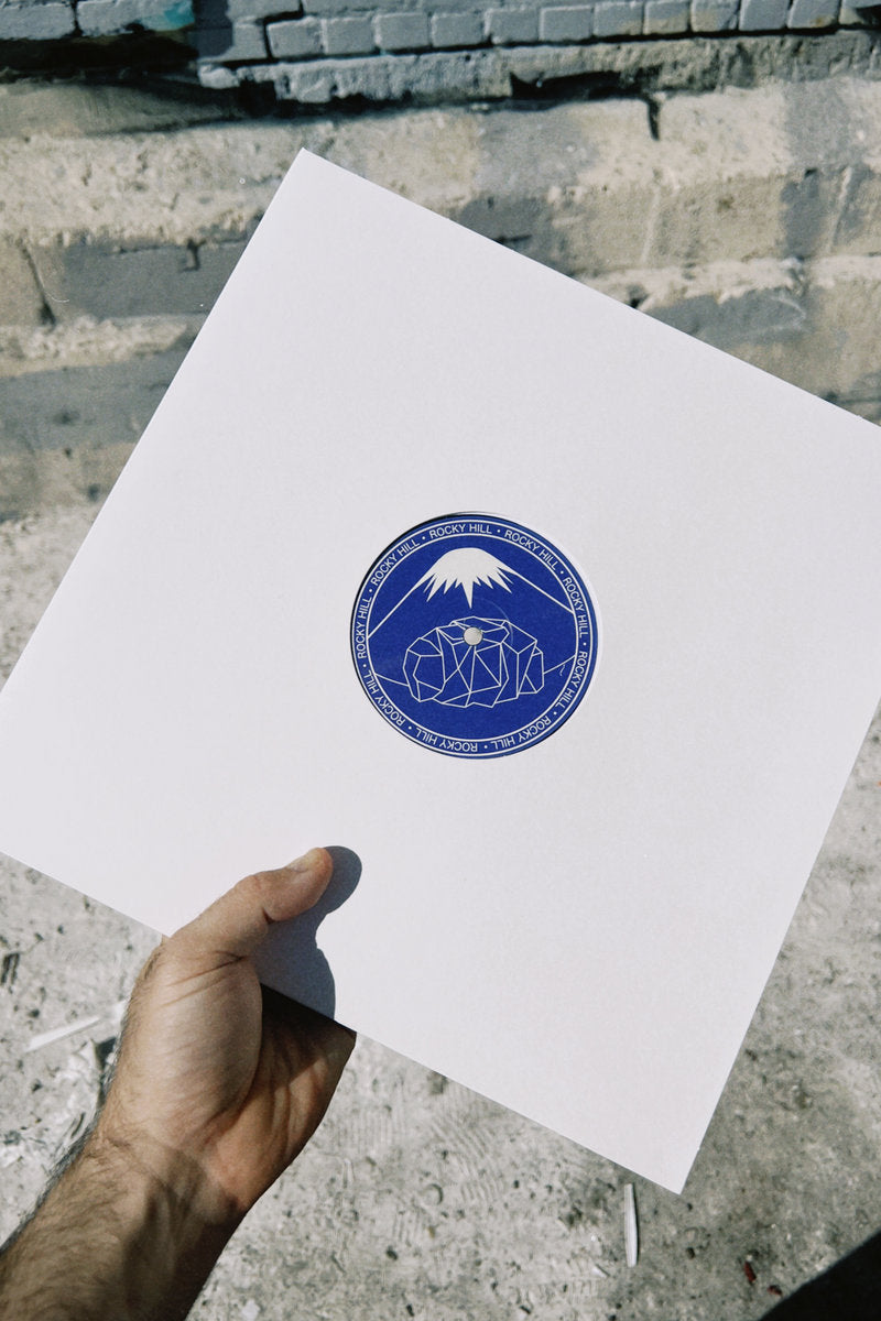 Contraportada del vinilo Paul West – Blue Sun 12" EP Rocky Hill, funda blanca limpia con arte central azul del sello Rocky Hill.
