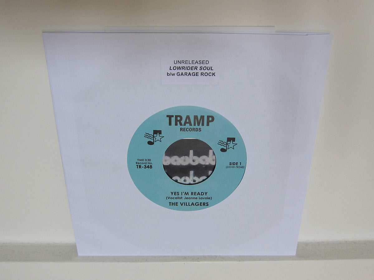 Funda blanca del vinilo The Villagers – Yes I'm Ready de Tramp Records, mostrando el disco parcialmente insertado y el texto “Unreleased Lowrider Soul b/w Garage Rock” en la parte superior.