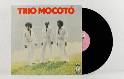 Funda y vinilo negro de Trio Mocotó – Trio Mocotó; portada del trío de blanco y etiqueta central rosa.